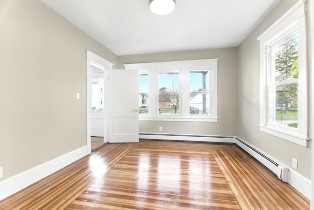 empty room with a wealth of natural light, baseboards, light wood-style flooring, and a baseboard radiator