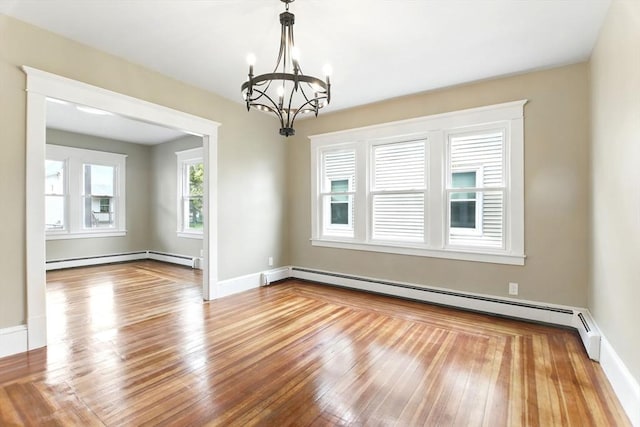 spare room with an inviting chandelier, wood-type flooring, baseboards, baseboard heating, and a baseboard heating unit