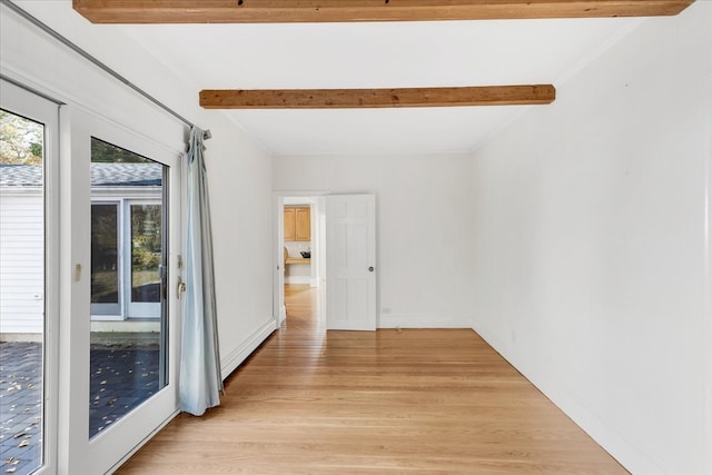 empty room featuring a baseboard heating unit, beamed ceiling, and light wood-type flooring