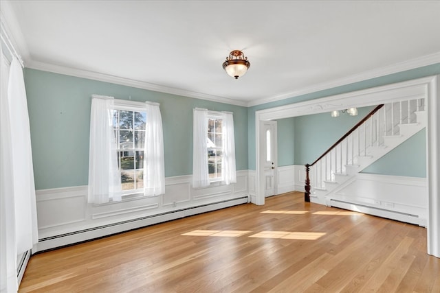 interior space featuring wood-type flooring, ornamental molding, and baseboard heating