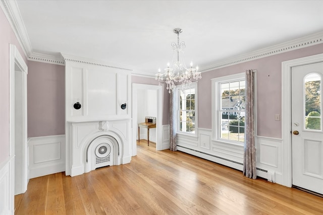 unfurnished living room featuring light hardwood / wood-style floors, crown molding, an inviting chandelier, and plenty of natural light