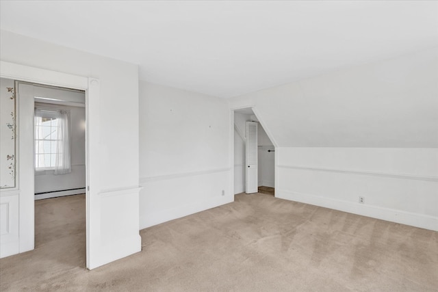 additional living space featuring a baseboard radiator, vaulted ceiling, and light carpet