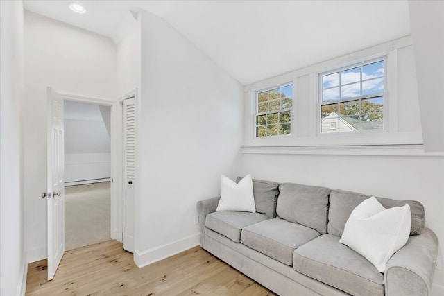 living room with light hardwood / wood-style flooring, lofted ceiling, and baseboard heating