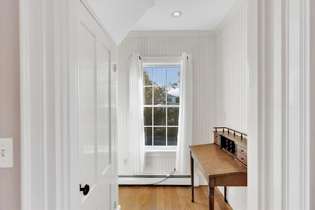 doorway to outside featuring ornamental molding, a baseboard heating unit, and light wood-type flooring