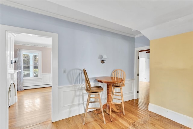 dining room featuring light hardwood / wood-style floors, crown molding, and baseboard heating