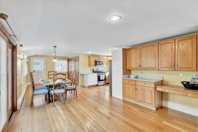 kitchen featuring light hardwood / wood-style floors, stainless steel appliances, lofted ceiling, and decorative light fixtures