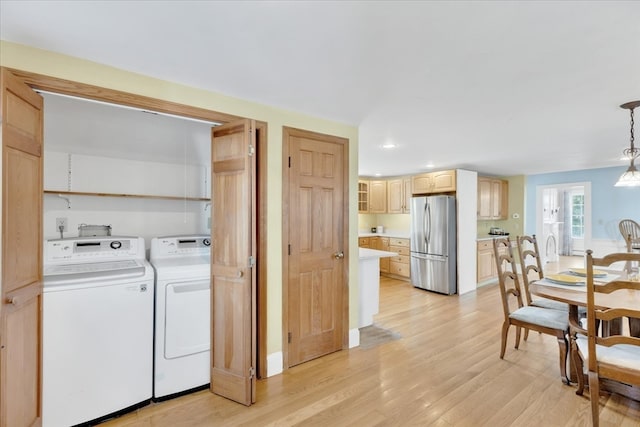 laundry area with light hardwood / wood-style floors and washing machine and dryer