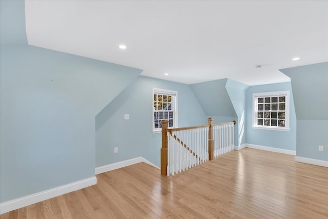 additional living space with lofted ceiling and light hardwood / wood-style flooring