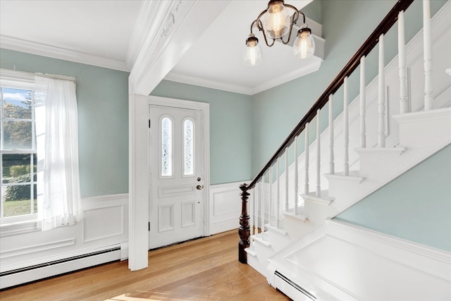 foyer with light wood-type flooring, ornamental molding, a baseboard heating unit, and plenty of natural light