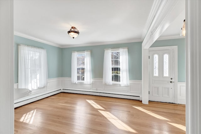 foyer entrance with ornamental molding, light hardwood / wood-style floors, and a healthy amount of sunlight