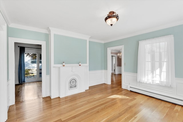 spare room featuring light hardwood / wood-style flooring, a baseboard heating unit, a notable chandelier, and crown molding