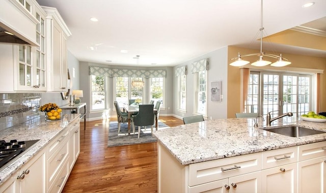 kitchen featuring light stone counters, sink, and hanging light fixtures