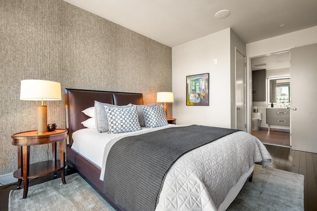 bedroom featuring wood finished floors, an accent wall, and wallpapered walls