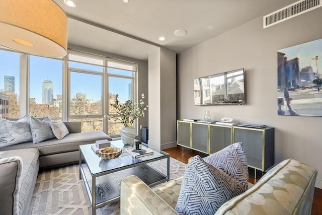 living room with visible vents, a view of city, wood finished floors, recessed lighting, and baseboards