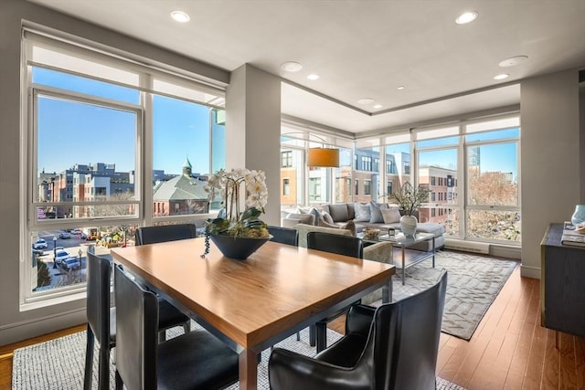 dining room with a city view, hardwood / wood-style flooring, and recessed lighting