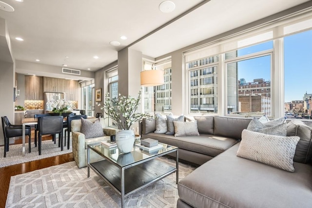 living room featuring recessed lighting, a healthy amount of sunlight, a view of city, and wood finished floors