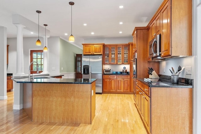 10 Londonderry Ln, Georgetown, MA 01833 - kitchen featuring appliances with stainless steel finishes, decorative columns, brown cabinetry, light wood finished floors, and glass insert cabinets