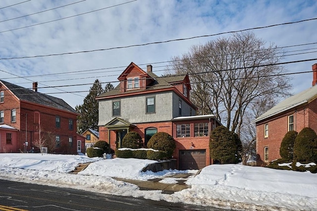 american foursquare style home featuring brick siding, a chimney, and an attached garage