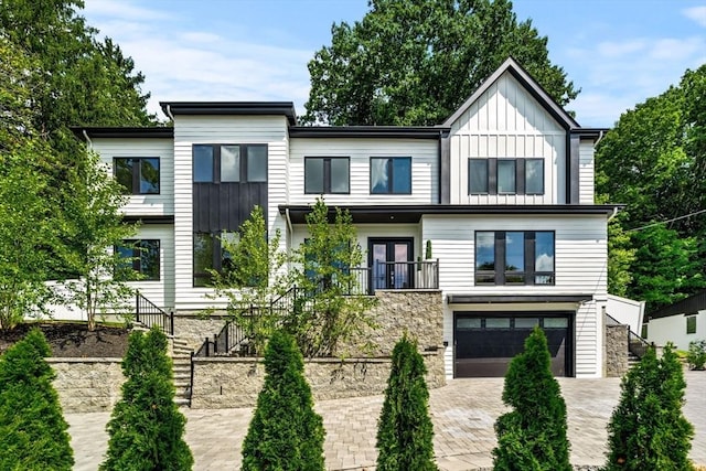 view of front of property featuring a garage, stairway, decorative driveway, french doors, and board and batten siding