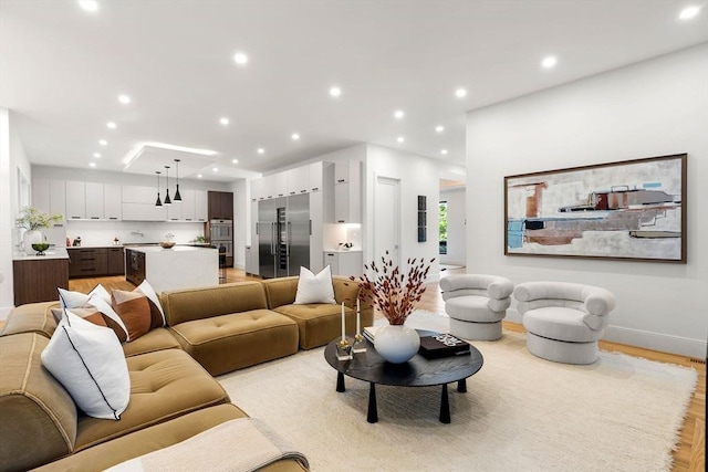 living room with baseboards, light wood finished floors, and recessed lighting