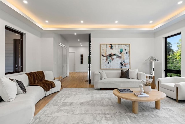 living area with light wood-style flooring, a raised ceiling, and recessed lighting