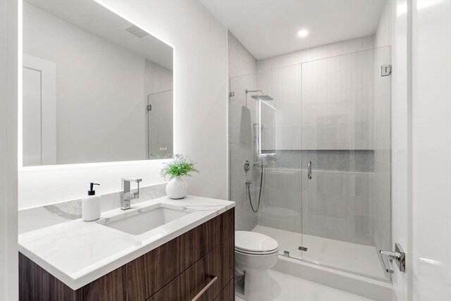 bathroom with a stall shower, vanity, and toilet