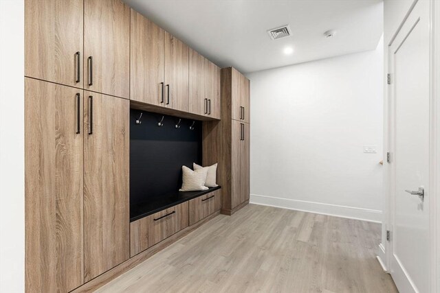 mudroom with light wood-style floors, baseboards, and visible vents