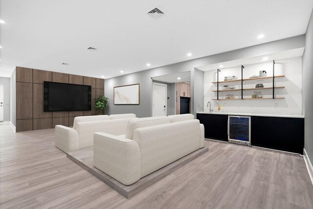 living area with light wood finished floors, recessed lighting, visible vents, wet bar, and beverage cooler