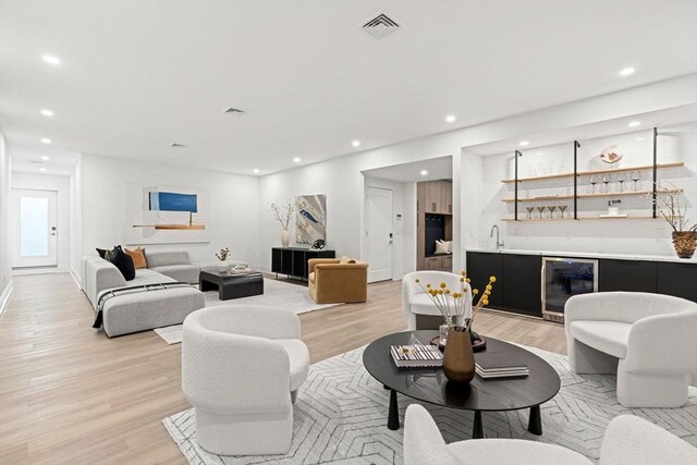 living room with recessed lighting, beverage cooler, visible vents, wet bar, and light wood finished floors