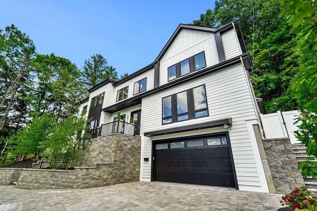 view of front of home with an attached garage, decorative driveway, and board and batten siding