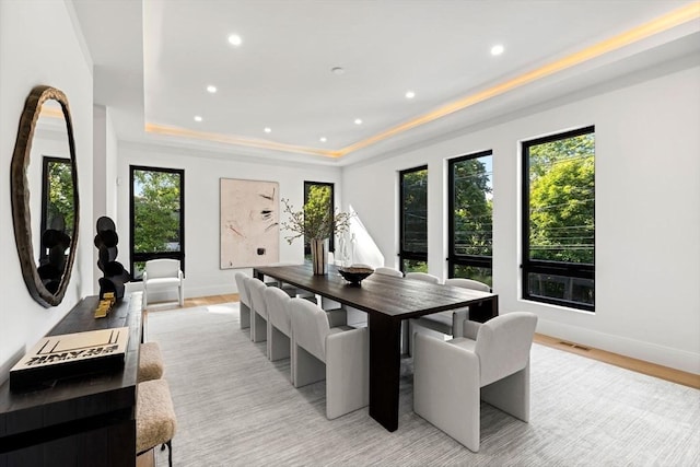 dining area featuring baseboards, recessed lighting, a raised ceiling, and light wood-style floors