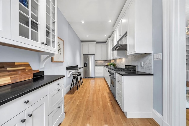 318 Commonwealth Ave Unit 3, Boston, MA 02115 - kitchen featuring appliances with stainless steel finishes, range hood, dark countertops, glass insert cabinets, and backsplash