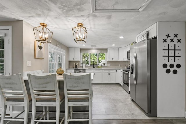 369 Vernon St, Wakefield, MA 01880 - kitchen featuring stainless steel appliances, light countertops, white cabinetry, a kitchen bar, and a chandelier