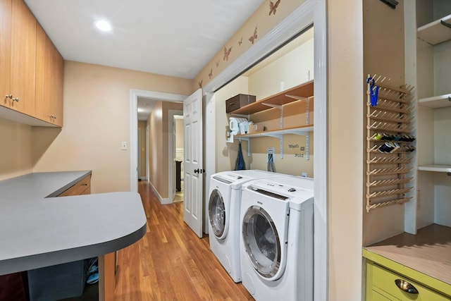 washroom featuring washing machine and dryer, cabinets, and light wood-type flooring