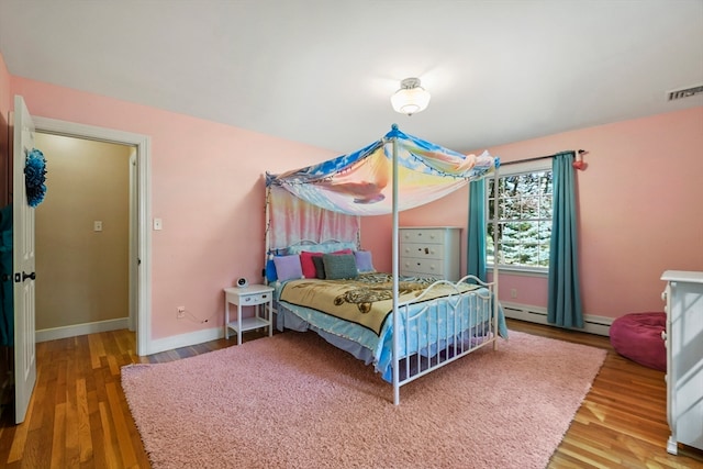 bedroom featuring baseboard heating and hardwood / wood-style floors