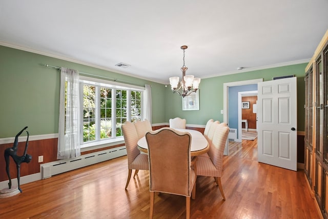 dining space featuring an inviting chandelier, a baseboard heating unit, wood-type flooring, and crown molding