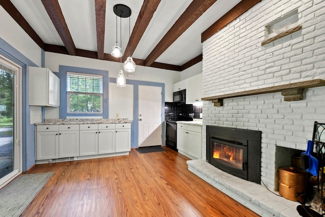 kitchen with light hardwood / wood-style flooring, white cabinetry, black appliances, and pendant lighting