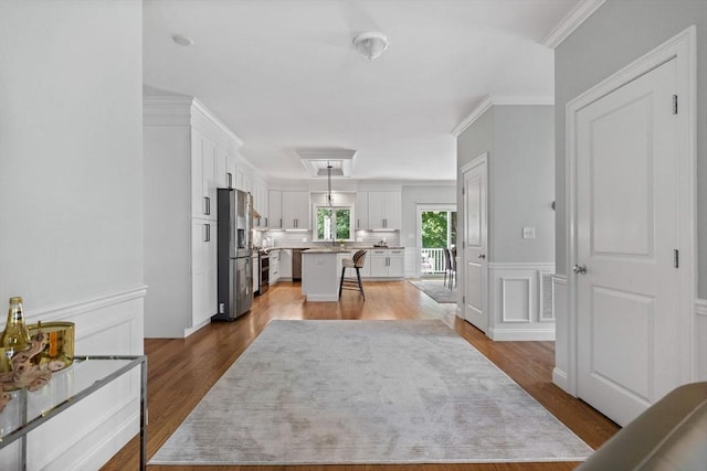 125 Ash St Unit 1, Waltham, MA 02453 - kitchen featuring stainless steel appliances, a kitchen bar, white cabinetry, a kitchen island, and wood finished floors