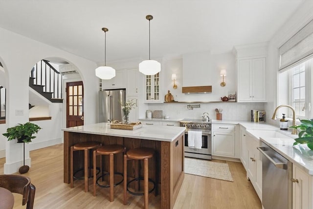 kitchen with light wood-style flooring, high quality appliances, a kitchen island, and a sink