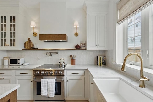 kitchen with white cabinets, a sink, high end range, and white microwave