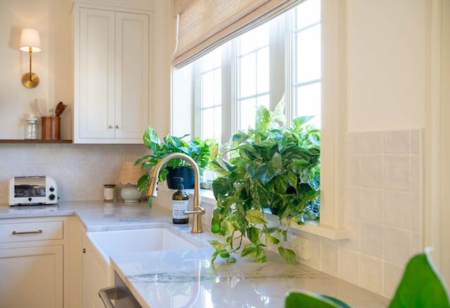 interior space featuring a toaster, a sink, white cabinets, decorative backsplash, and dishwasher