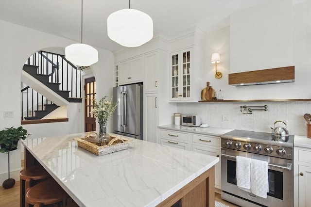 kitchen featuring glass insert cabinets, backsplash, high quality appliances, and white cabinets