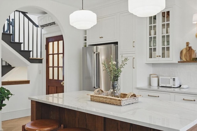 kitchen with glass insert cabinets, arched walkways, white cabinetry, and high quality fridge