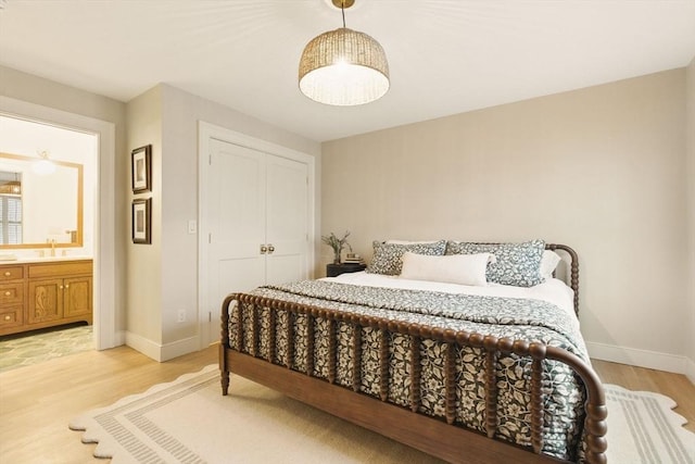 bedroom with light wood-style floors, baseboards, and a sink