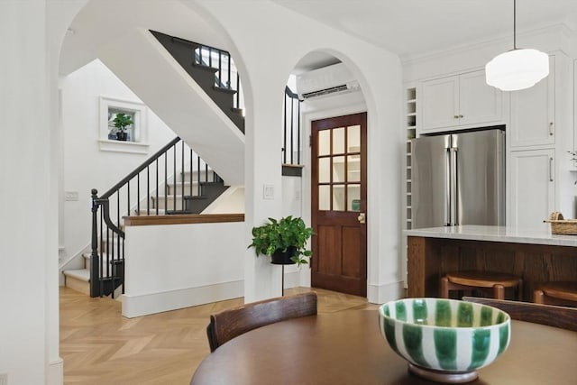 dining room with arched walkways, an AC wall unit, and stairway