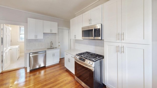 kitchen featuring decorative backsplash, white cabinetry, sink, and appliances with stainless steel finishes