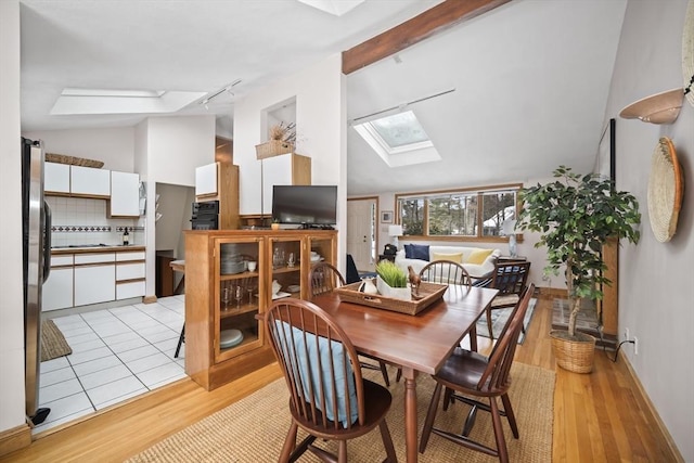 dining area featuring lofted ceiling with skylight and light wood finished floors