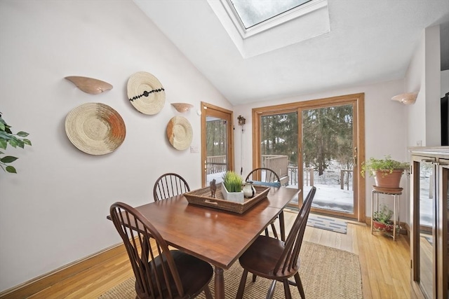 dining room with lofted ceiling with skylight and light wood finished floors