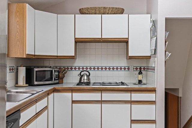 kitchen featuring tasteful backsplash, white cabinetry, stainless steel appliances, and light countertops