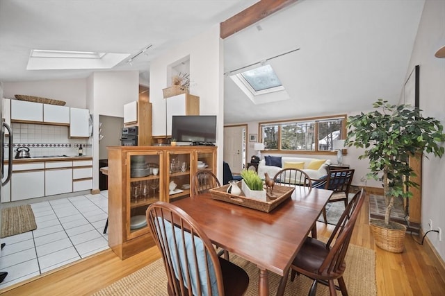 dining space with lofted ceiling with skylight and light wood finished floors